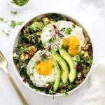 Nutritious breakfast salad bowl with fried eggs, sautéed greens, roasted vegetables, avocado and microgreens, featuring fresh ingredients from The Greensted grocery store in downtown Zumbrota.